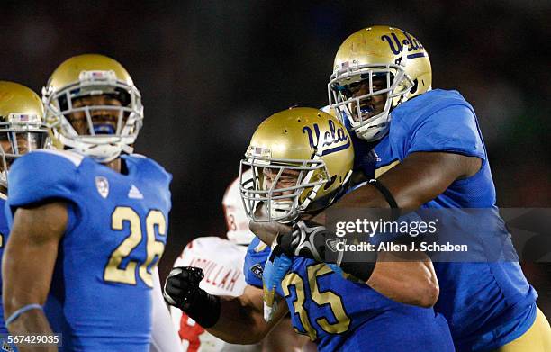 Defenders Andrew Abbott, left, and Datone Jones, right, celebrate Jordan Zumwalt, center after he sacked Nebraska quarterback Taylor Martinez in the...