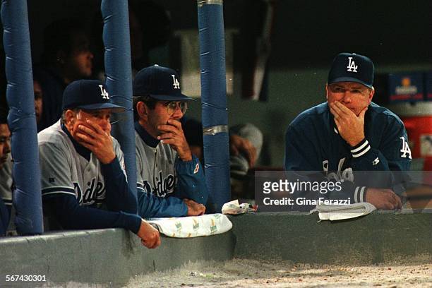 The LA Dodgers coaching staff from left, third base coach Joe Almalfitano, pitching coach David Wallace, manager Bill Russell in the 9th inning sit...