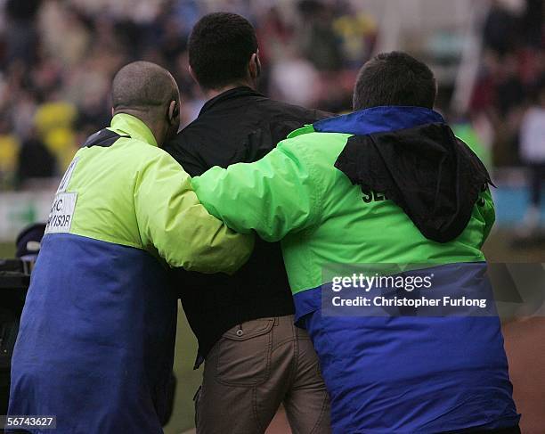 Middlesbrough fan is lead off the pitch by stewards after throwing his season ticket at manager Steve McLaren during the Barclays Premiership match...