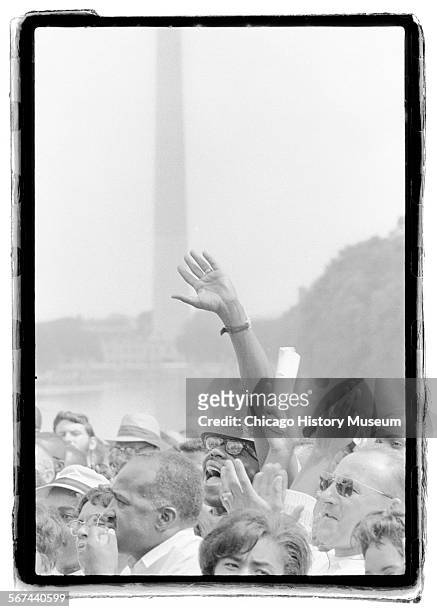 Man raises his hand amidst a crowd of people during the March on Washington for Jobs and Freedom, Washington DC, August 28, 1963.
