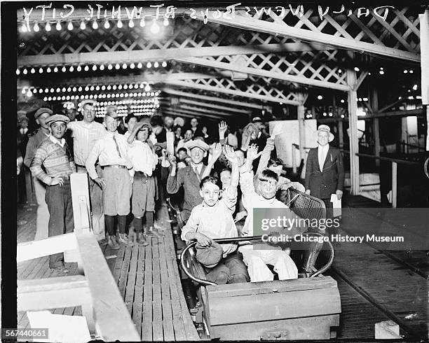 Informal full-length portrait of Chicago Daily News newsboys sitting in roller coaster cars on a roller coaster at the White City amusement park,...