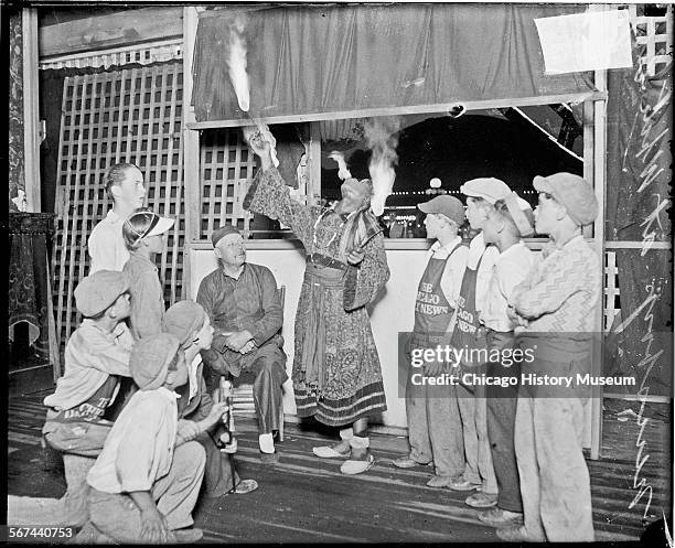 Image of a person wearing a costume, eating fire in front of a booth at White City amusement park, located at 63rd Street and South Parkway, now...