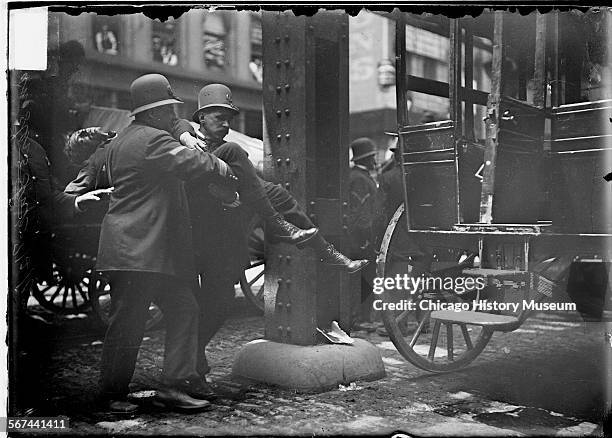 Wounded man being carried to an ambulance by two policemen during the Teamsters Strike, Chicago, Illinois, June 4, 1902. The injured man was a...