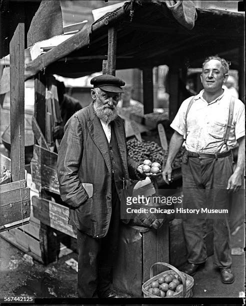 Portrait of a man holding lemons at the Maxwell Street market, Chicago, Illinois, circa 1920.
