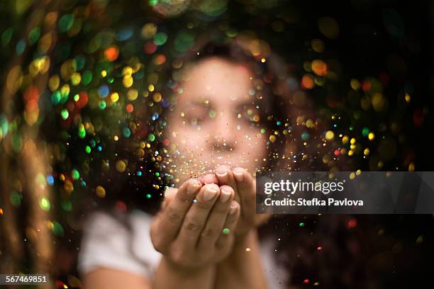 young woman blows glitter into the air - brocado fotografías e imágenes de stock