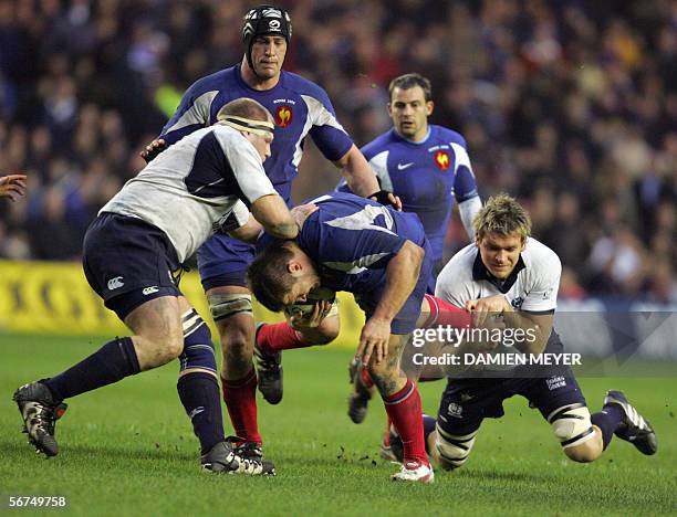 Edinburgh, UNITED KINGDOM: France's prop Sylvain Marconnet is tackled by Scotland's prop Bruce Douglas and Scotland's lock Scott McLeod , eyed by...