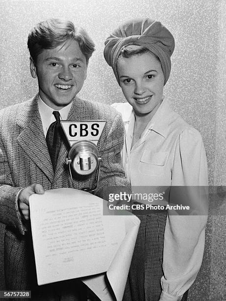 American actors Mickey Rooney & Judy Garland pose behind a microphone, a script in hand, during the CBS Lux Radio Theater broadcast of 'Strike Up the...