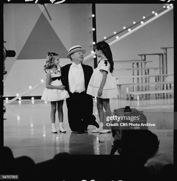American actor Mickey Rooney performs on his knres with two unidentified girls during an episode of 'The Judy Garland Show,' June 24, 1963.