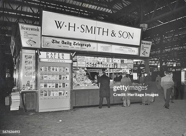 Smith's bookstall at Waterloo Station, Lambeth, London, 1960. Bookstall on the station concourse, selling newspapers and magazines. Men wait at the...