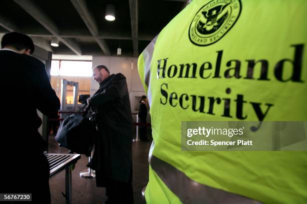 As a U.S. Department of Homeland Security official stands by, commuters place bags onto a weapon-detection machine at Exchange Place station on the...