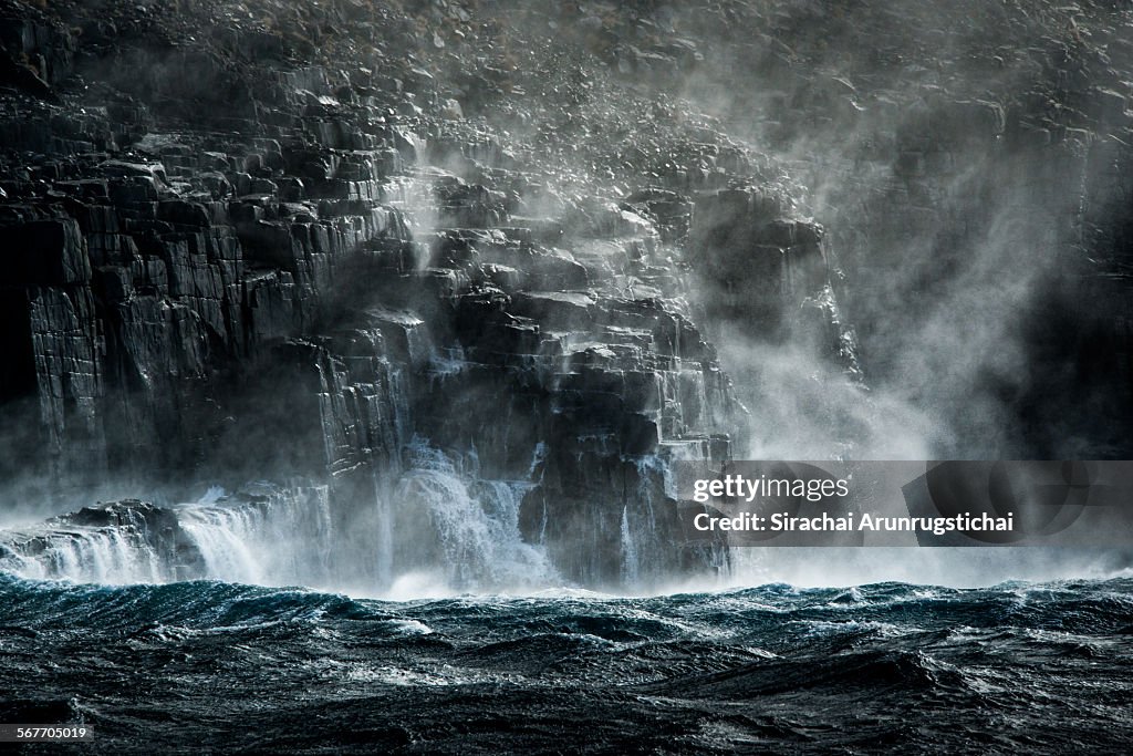 Dolerite cliff with waves under ray of light