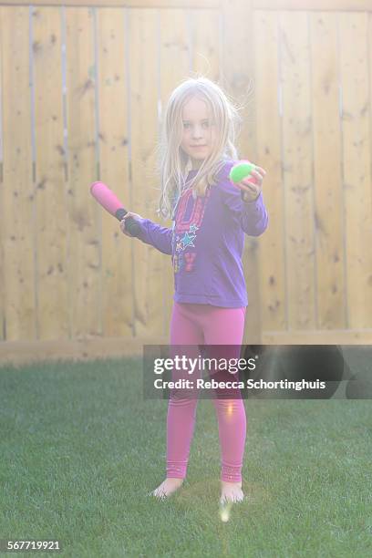 young girl hitting ball with bat in backyard - backyard baseball stock pictures, royalty-free photos & images