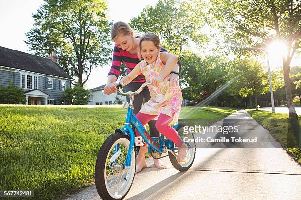 babysitter teaching little girl how to ride a bike - missouri mittlerer westen stock-fotos und bilder