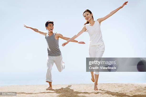 romantic couples running on the beach - 飛行機のまね ストックフォトと��画像