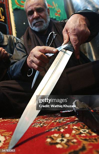 An Iraqi Shiite man cleans his sword as he prepares to flagellate himself in honour of Imam Hussein's death anniversary on February 8, 2006 in the...