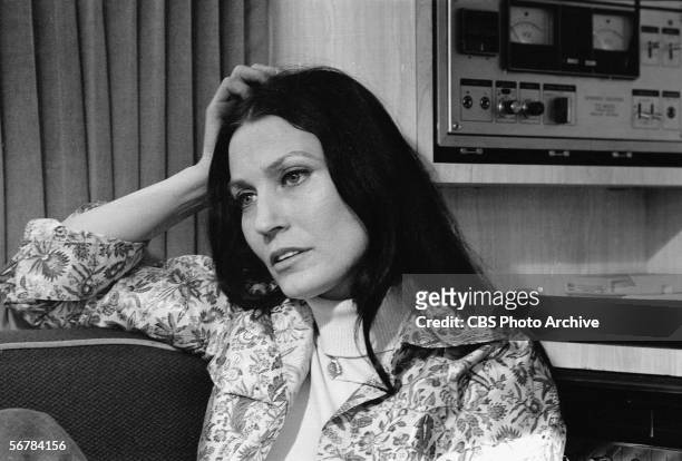 American country music singer Loretta Lynn rests her head on her hand and reclines on a couch near some audio equipment, February 24, 1975.