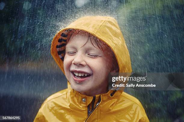 happy smiling little boy in the rain - lluvia fotografías e imágenes de stock