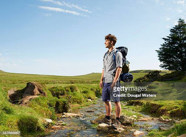 hiker crossing rocky stream in countryside. - shorts stock pictures, royalty-free photos & images