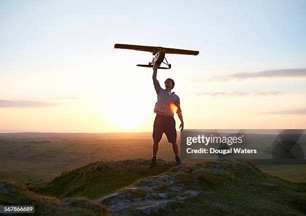 man holding model air plane over head at sunset. - best before stockfoto's en -beelden