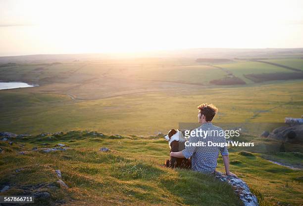 man sitting with dog at sunset. - chien et maitre photos et images de collection