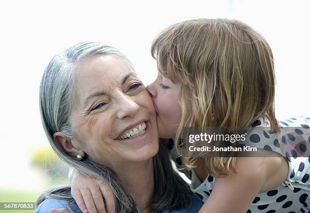 five year old girl kisses her grandmother - jonge senioren in groep stockfoto's en -beelden