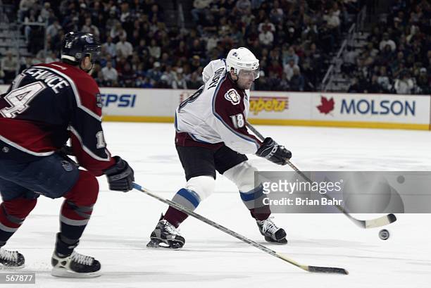 Center Chris Drury of the Colorado Avalanche skates with the puck past defenseman Scott Lachance of the Vancouver Canucks during the NHL game at the...
