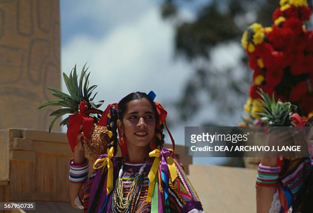 Women with pineapples and wearing traditional costumes during the celebrations at the Guelaguetza festival, Oaxaca, Mexico.