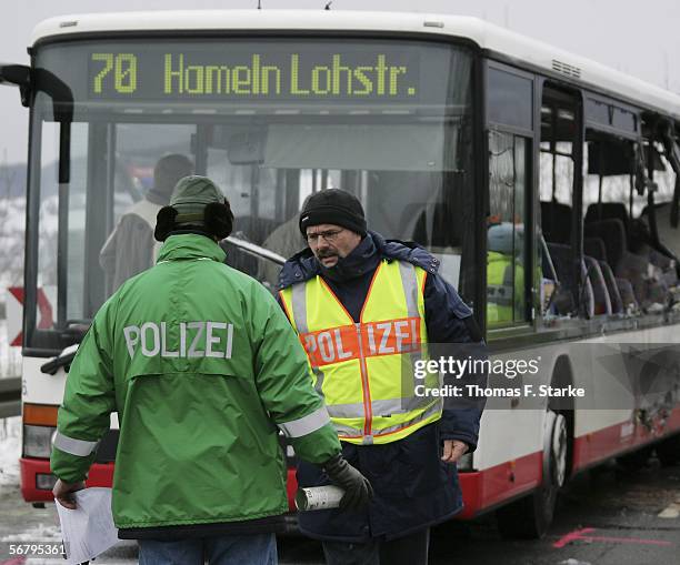 Two policemen stand beside a damaged bus after it was hit by a truck on February 9, 2006 in Coppenbruegge, Germany. Two children and one adult died...