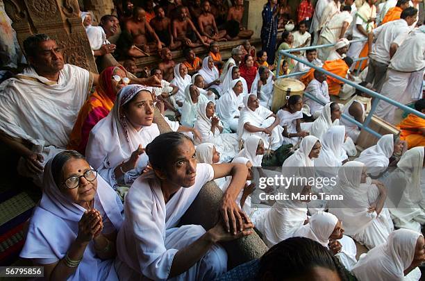 Jain nuns watch holy liquid pour off the monolithic statue of the Jain sage 'Gomateshvara' during the Mahamastak Abhisheka ceremony February 9, 2006...