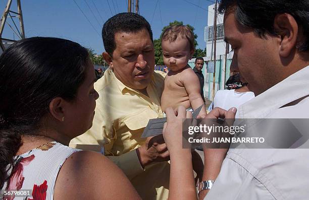 El presidente de Venezuela Hugo Chavez , carga una nina mientras conversa con su madre, en el estado petrolero de Zulia-Maracaibo, ubicado a 500 km...