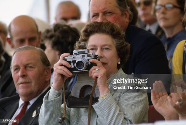 Queen Elizabeth II taking a picture with her camera at the Royal Windsor Horse Show.