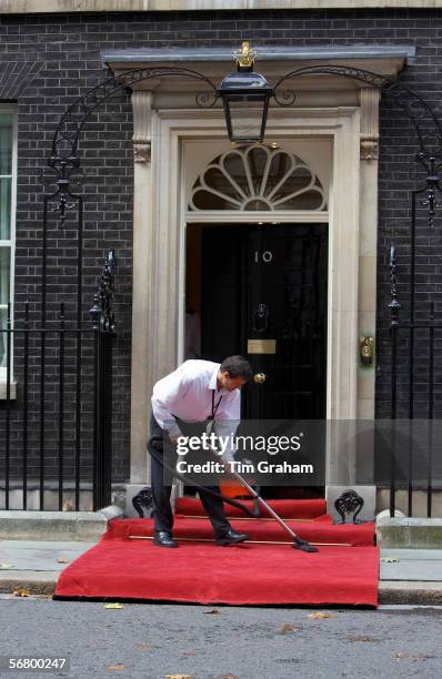 Cleaner hoovers the carpet outside Number 10 Downing Street, the home of the British Prime Minister, London, United Kingdom.