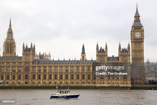 Police launch passes The Houses of Parliament, Westminster, River Thames, London, UK.