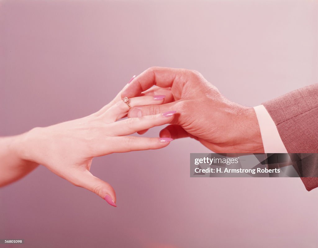 Man placing engagement ring on woman's finger
