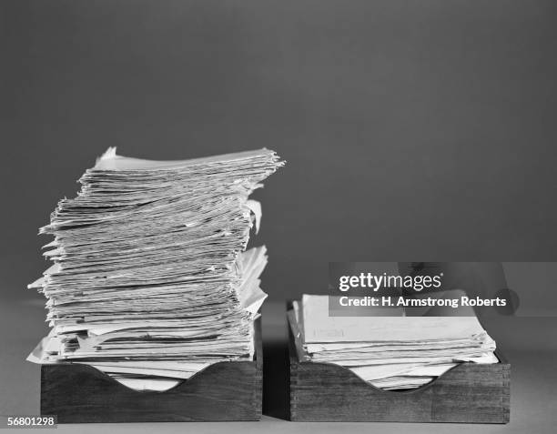 1960s: Office paper trays, In tray overflowing, Out tray with smaller pile.