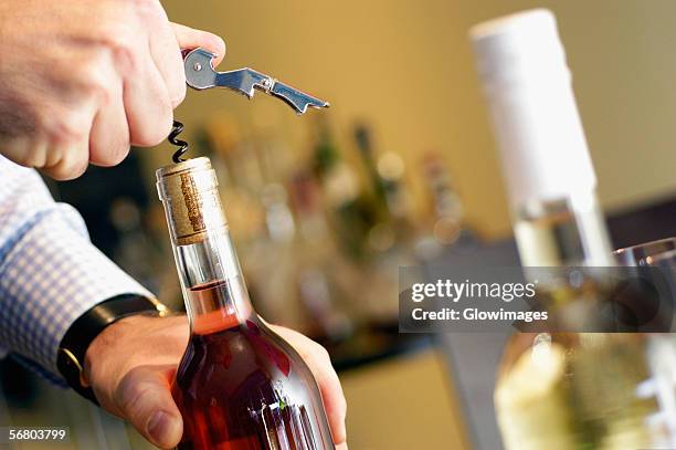 close-up of a man unscrewing cork of a wine bottle - wine cork stock pictures, royalty-free photos & images