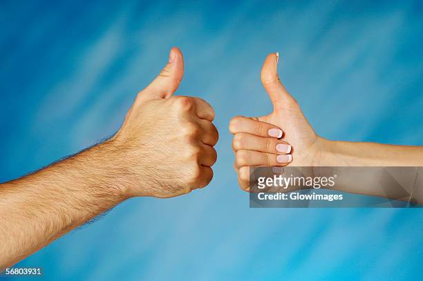 close-up of a man and a woman's hands making a thumbs up sign - thumb stock-fotos und bilder