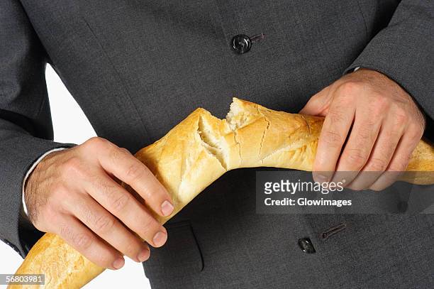 mid section view of a businessman breaking a loaf of bread - businessman broke stock-fotos und bilder