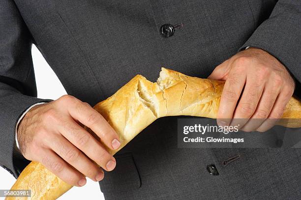 mid section view of a businessman breaking a loaf of bread - breaking bread stock pictures, royalty-free photos & images