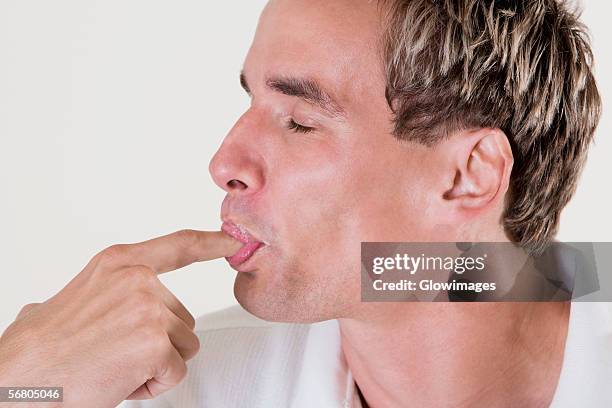 close-up of a mid adult man licking his finger - suck stock pictures, royalty-free photos & images