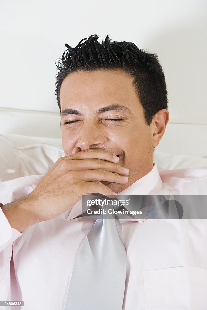 Businessman covering his mouth with his hand while yawning