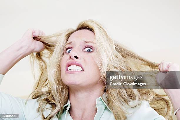 portrait of a young woman pulling her hair and clenching her teeth - hair pulling stock pictures, royalty-free photos & images