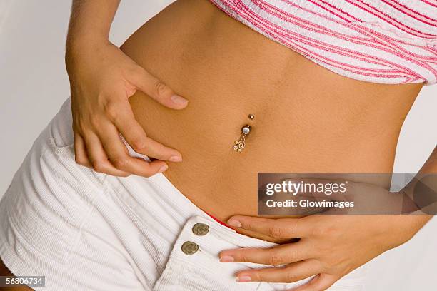 mid section view of a young woman with a pierced belly button - belly button piercing foto e immagini stock
