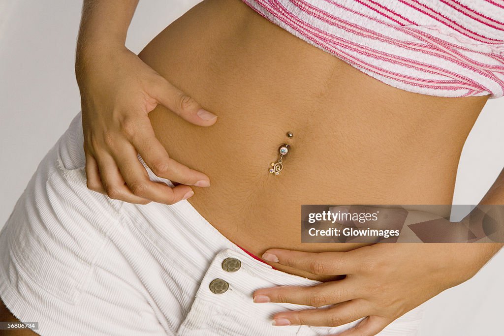 Mid section view of a young woman with a pierced belly button