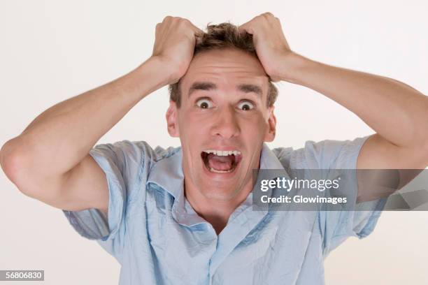 portrait of a young man pulling his hair - de-haren-uit-het-hoofd-trekken stockfoto's en -beelden