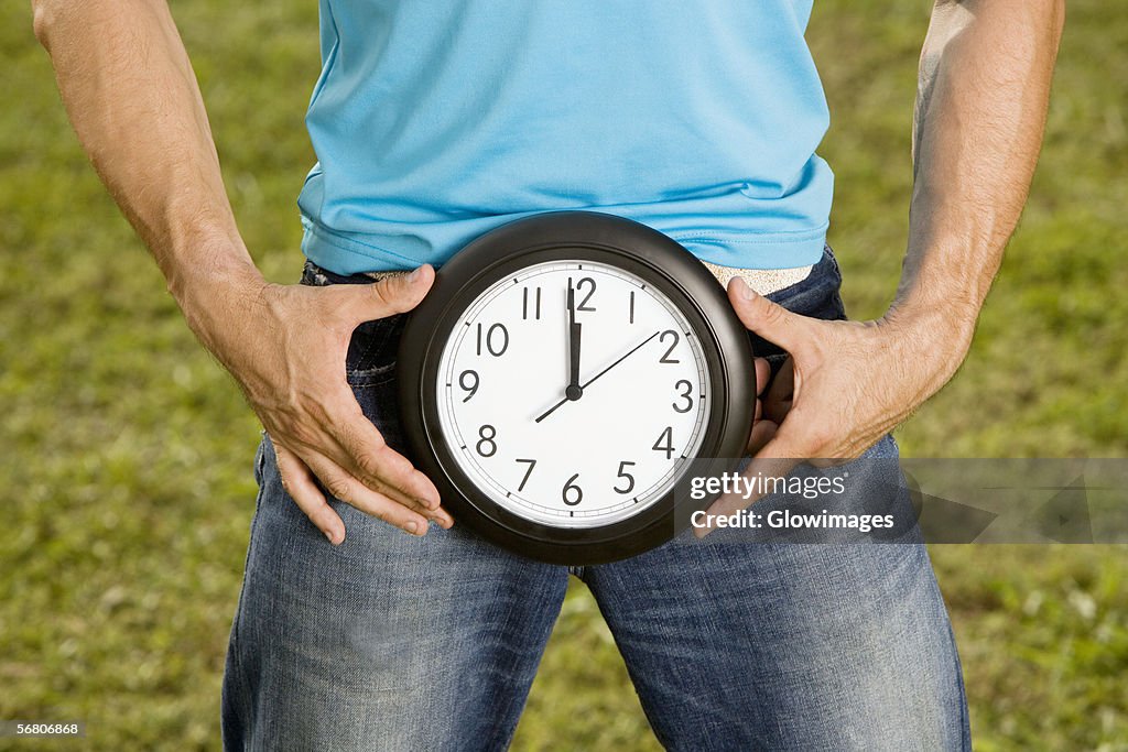 Close-up of a young man holding a clock