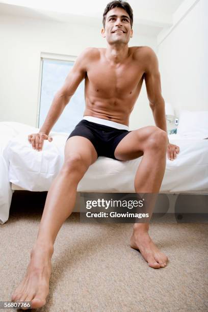 low angle view of a mid adult man sitting on a bed - barefoot floor stock pictures, royalty-free photos & images