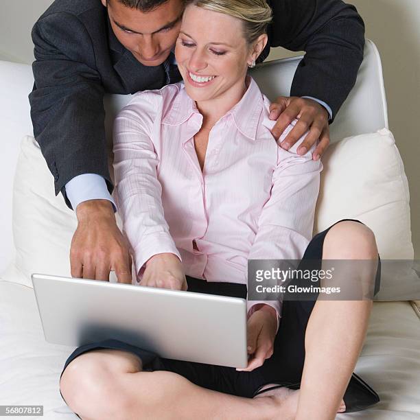 high angle view of a businessman and a businesswoman using a laptop - bending over in skirt stock-fotos und bilder
