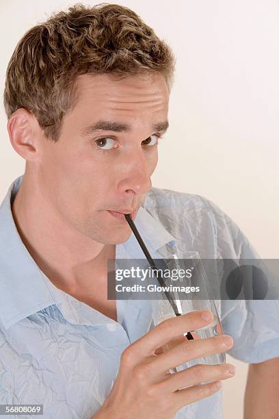 portrait of a mid adult man drinking water with a straw - rietje los stockfoto's en -beelden