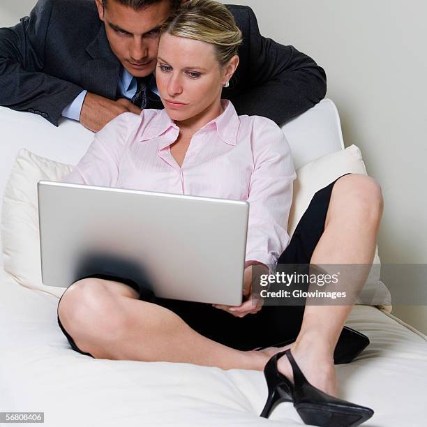 close-up of a businessman and a businesswoman looking at a laptop - bending over in skirt stock-fotos und bilder